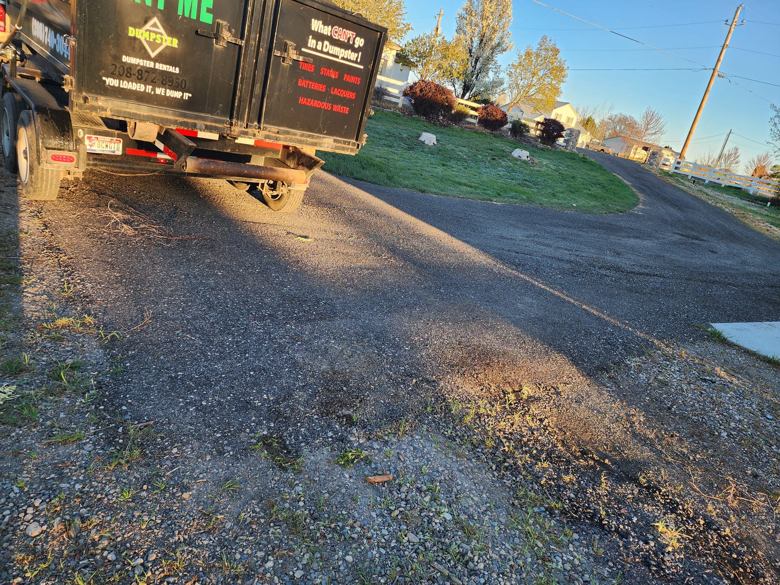 Rear doors of a Diamond Dumpster bin at golden hour, listing prohibited items: tires, stains, paints, batteries, lacquers, hazardous waste